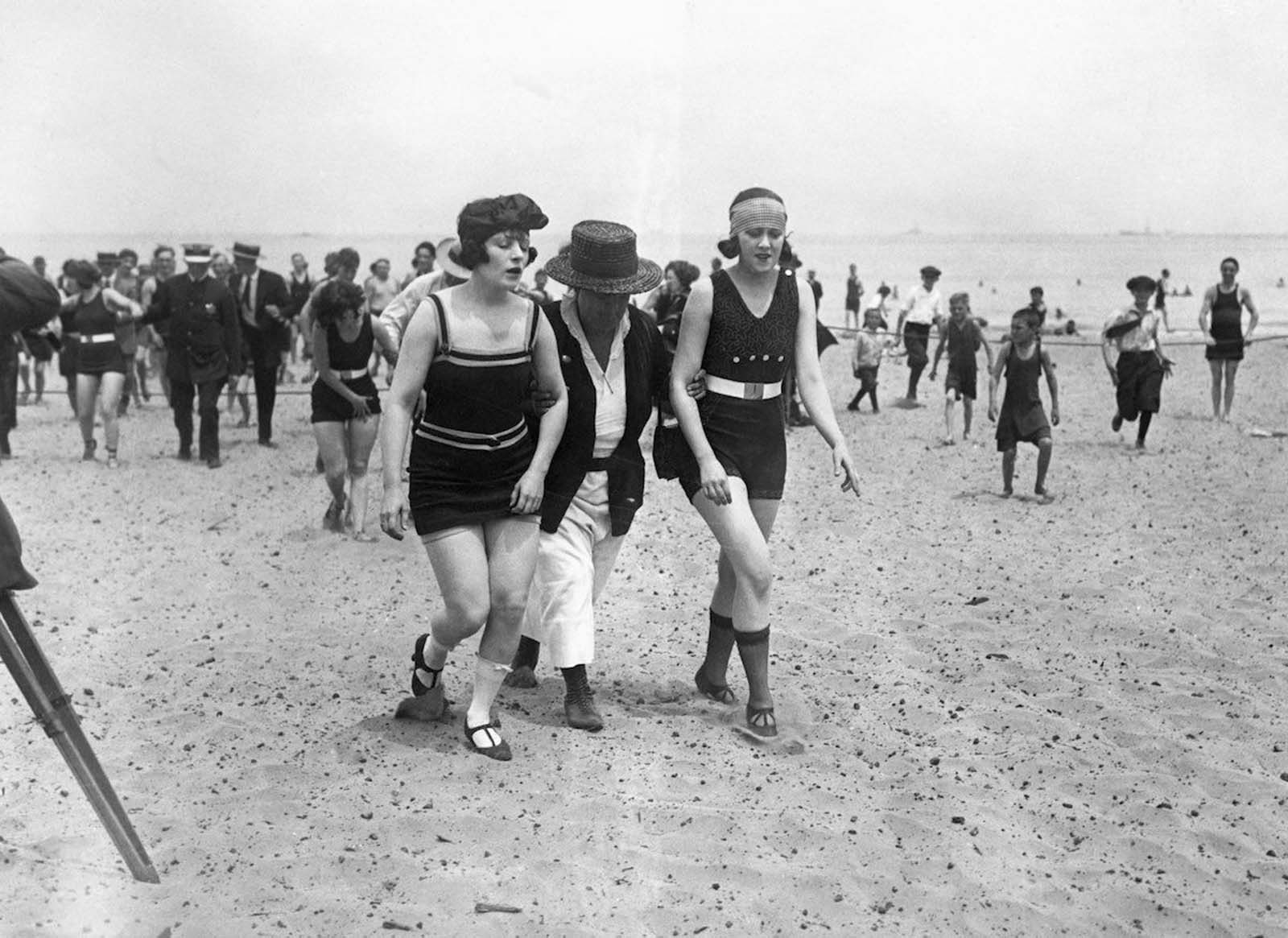 Two bathers being escorted off the beach by a police woman. Chicago, 1922.