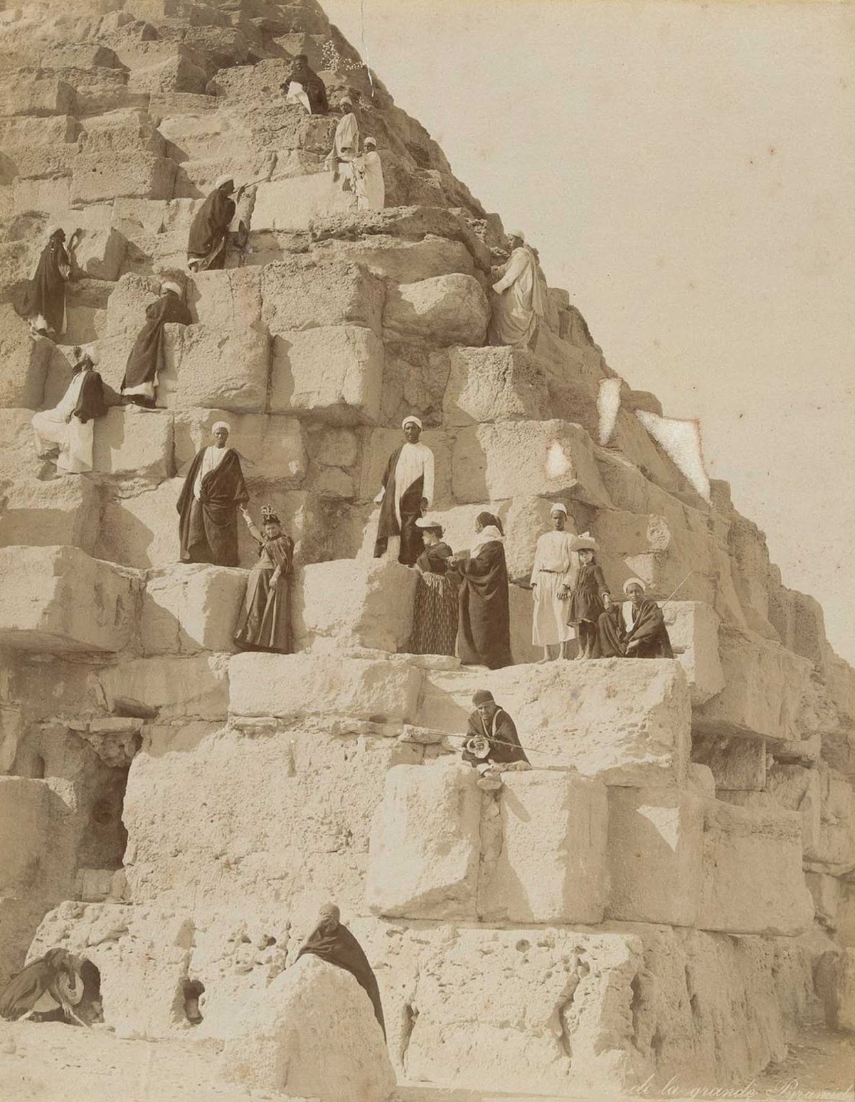 European tourists and local guides climb one of the pyramids at Giza.