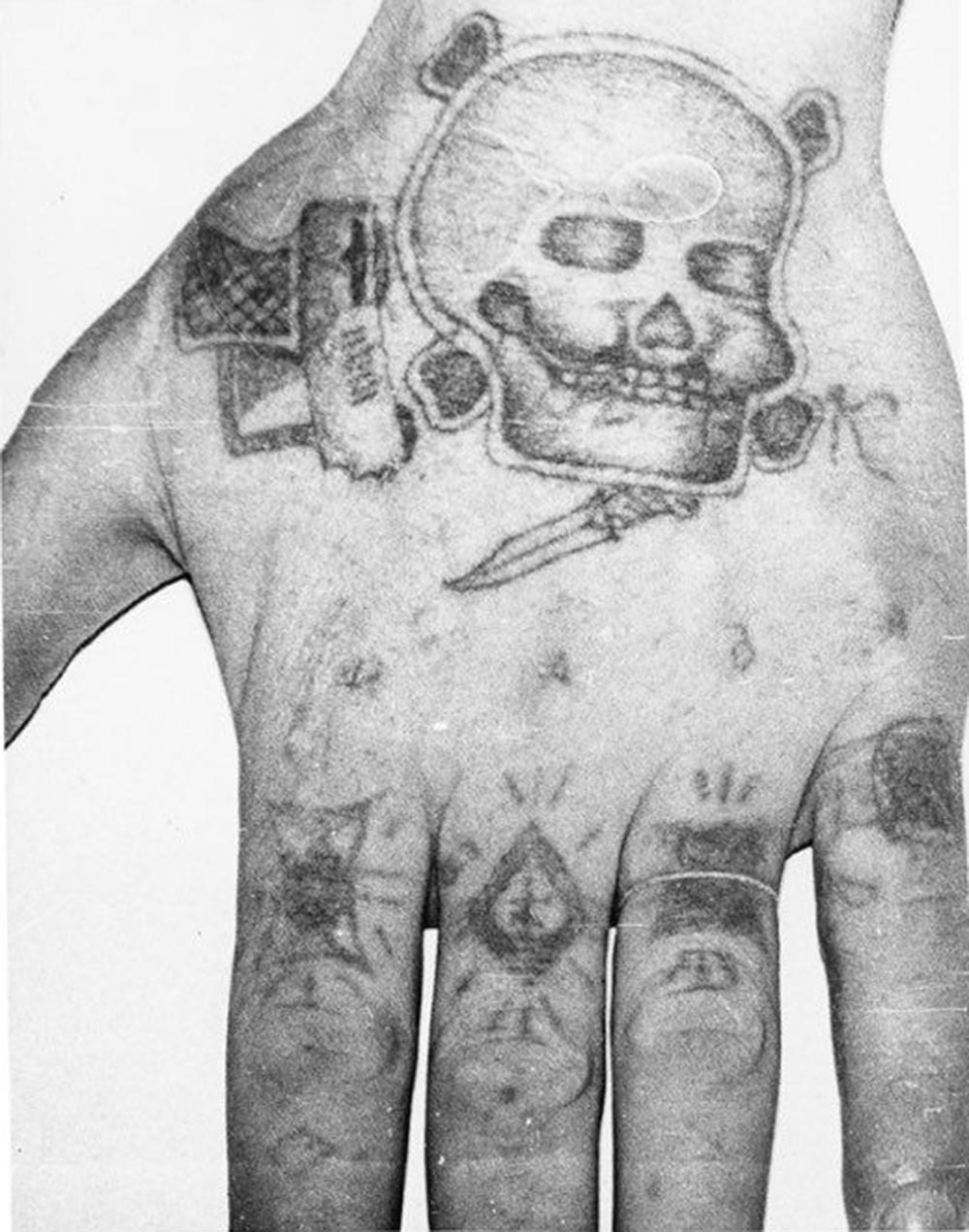Text across the knuckes reads NADYA (womans name). The ‘ring’ on the forefinger stands for ‘Rely on no one but yourself’, a ‘patsan’ one of the most privileged inmates VTK. Middle finger ‘the thieves cross’ of a pickpocket. Third finger: ‘I served my time in full’, ‘From start to finish’, ‘Went without parole’, the prisoner served his complete sentence with no remission for working with the system. Little finger ‘The dark life’ the bearer spent a lot of time in a punishment cell. The skull and crossbones, gun, knife and letter ‘K’[iller] denote a murderer.