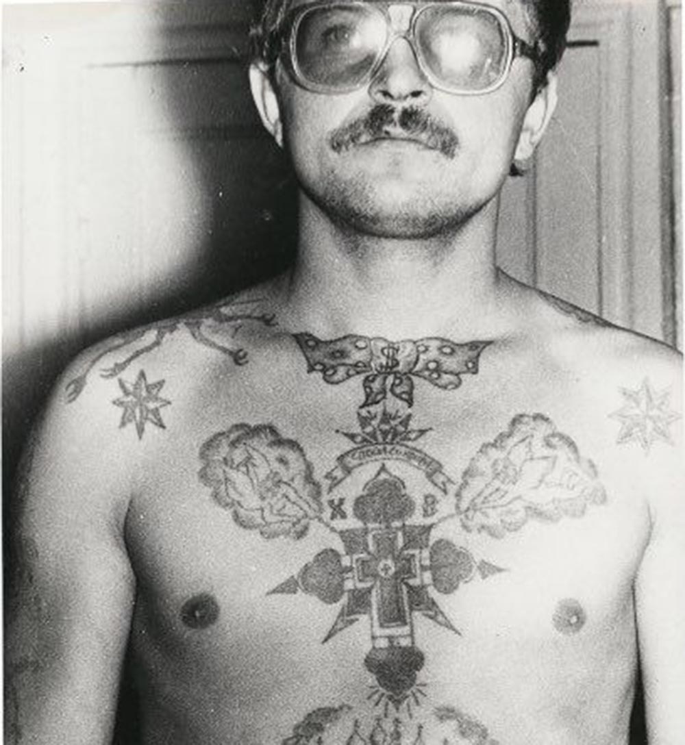 Text on the chest reads ‘Save and protect.' Text on either side of the cross reads ‘XV Hristos Voskres' (Christ has Risen). The eight-pointed stars on the clavicles denote a high-ranking thief. A bow tie tattooed on the neck is often found in strict regime colonies. Originally, bow ties were dishonourable tattoos. They were forcibly applied underneath the clavicle cat tattoos of pickpockets who had broken the ‘thieves’ code’ and sided with the authorities. Today, however, there is no stigma attached to them. The dollar sign on the bow tie shows the bearer is either a safecracker, money launderer or has been convicted for the theft of state property.