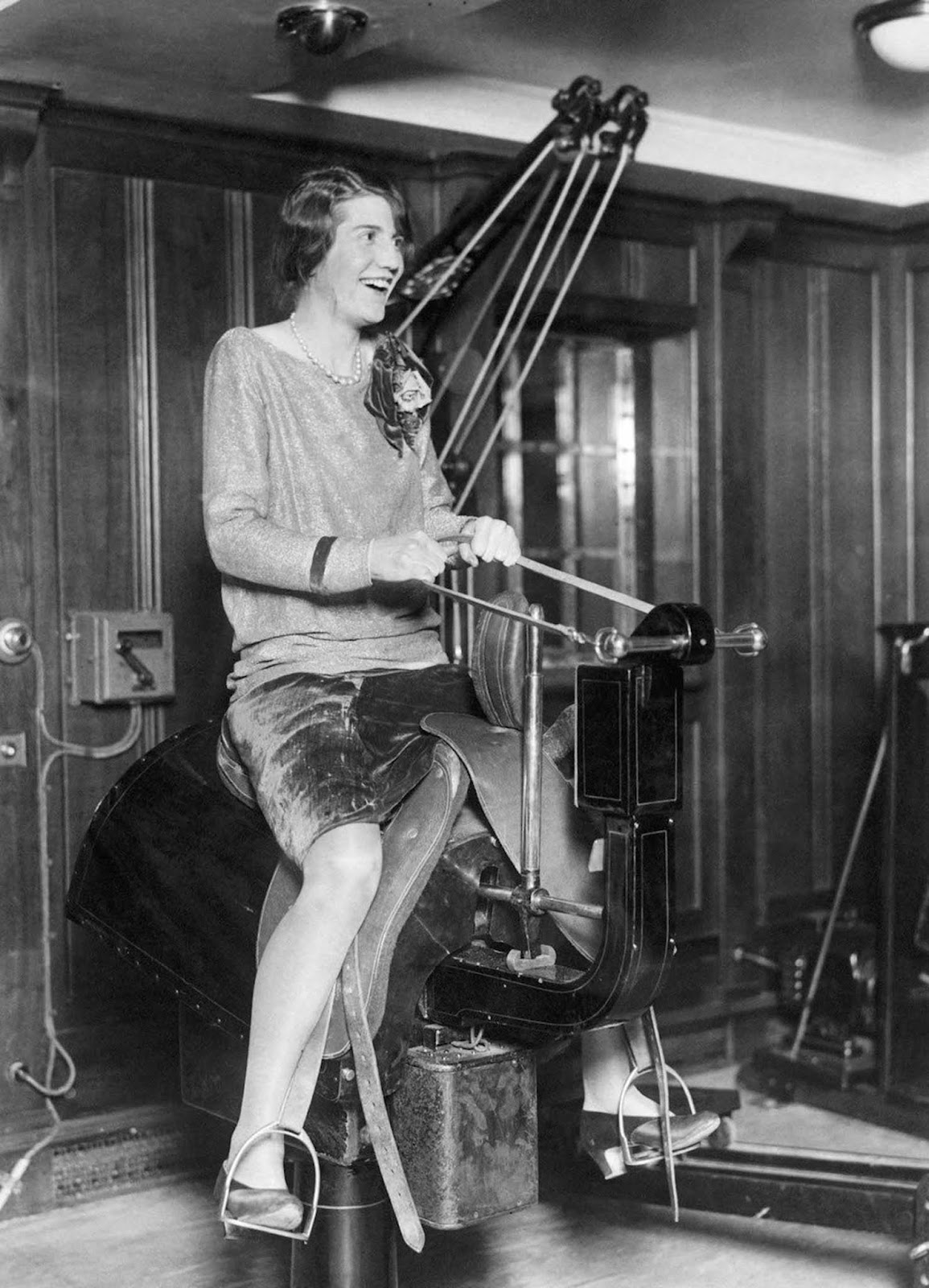 A young woman passenger riding the electric horse in the gym on the liner SS Bermuda. Mid 1920s.