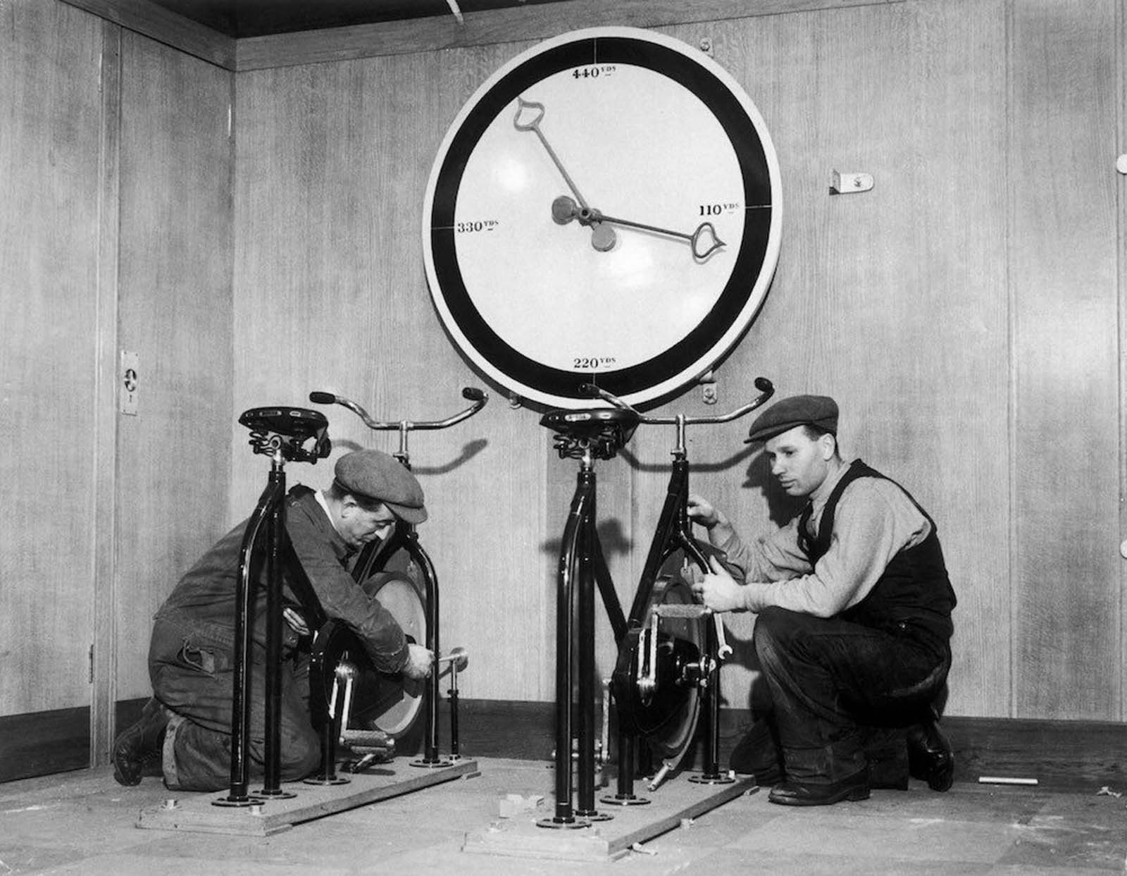 At the time of the installation of the English liner Queen Mary, workmen in the gymnasium of the ship are setting up exercise bikes, with an enormous meter indicating the distance covered. 1932.
