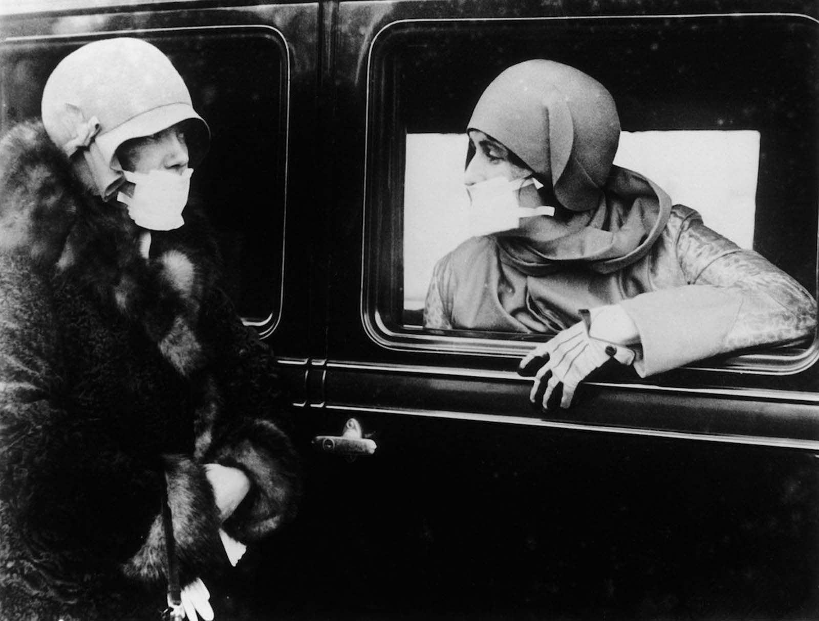Two women speak through flu masks during the epidemic. 1918.