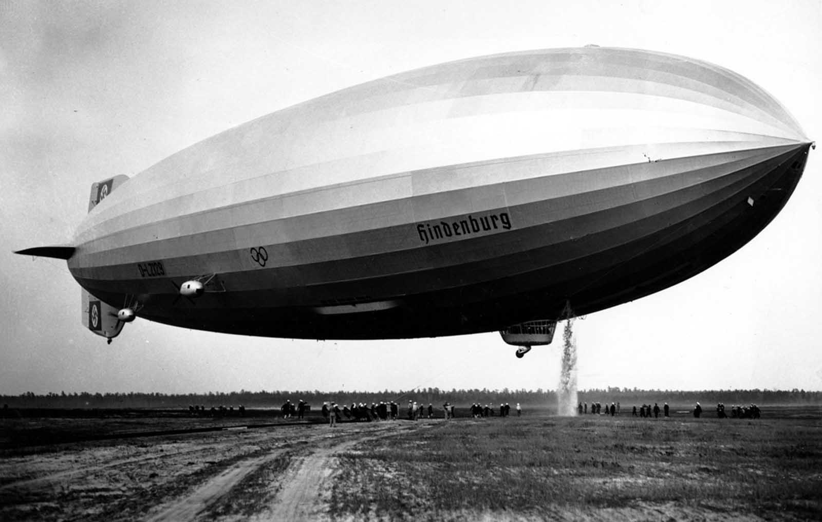 The Hindenburg dumps water to ensure a smoother landing in Lakehurst, New Jersey, on May 9, 1936. The airship made 17 round trips across the Atlantic Ocean in 1936, transporting 2,600 passengers in comfort at speeds up to 135 km/h (85 mph). The Zeppelin Company began constructing the Hindenburg in 1931, several years before Adolf Hitler's appointment as German Chancellor. For the 14 months it operated, the airship flew under the newly-changed German national flag, the swastika flag of the Nazi Party.