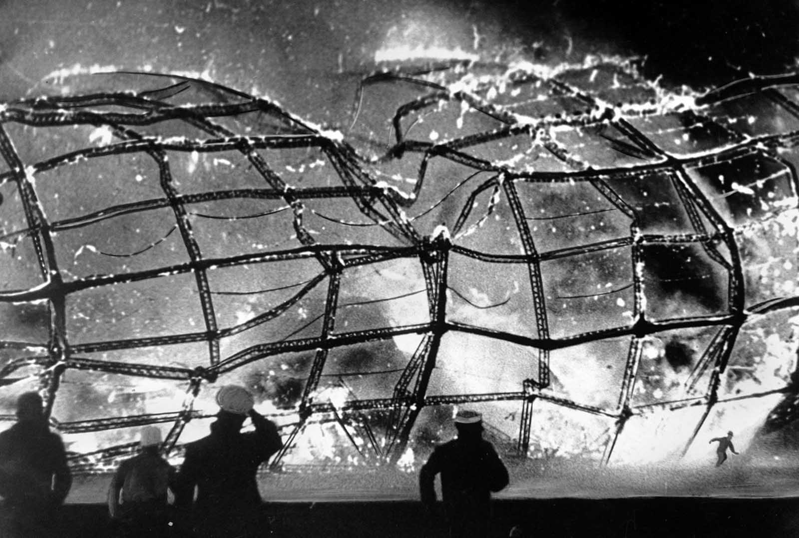 A survivor flees the collapsing structure of the airship Hindenburg.