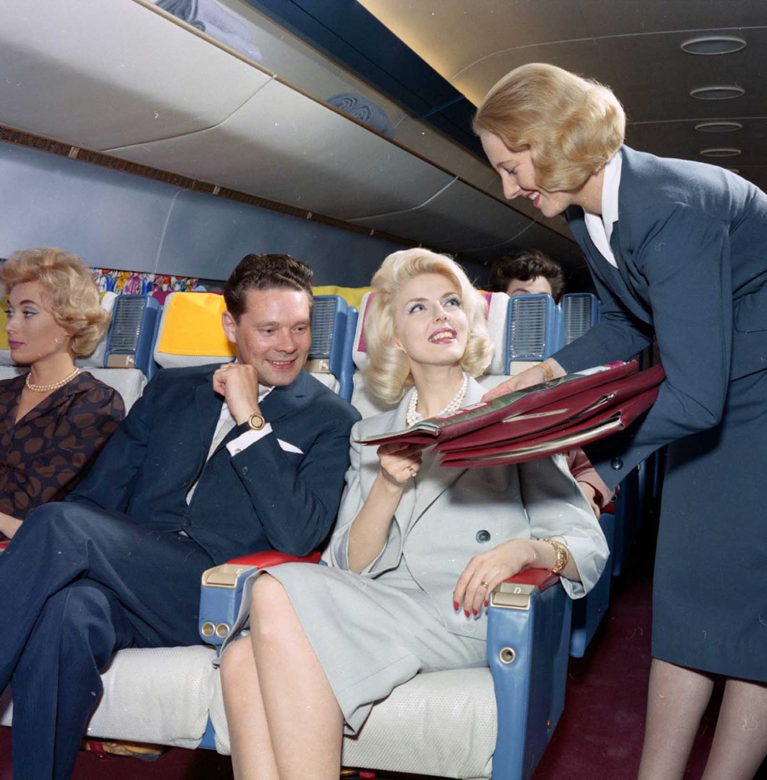The mid-1960s, a flight attendant with high fashion hairstyle brings the menu.