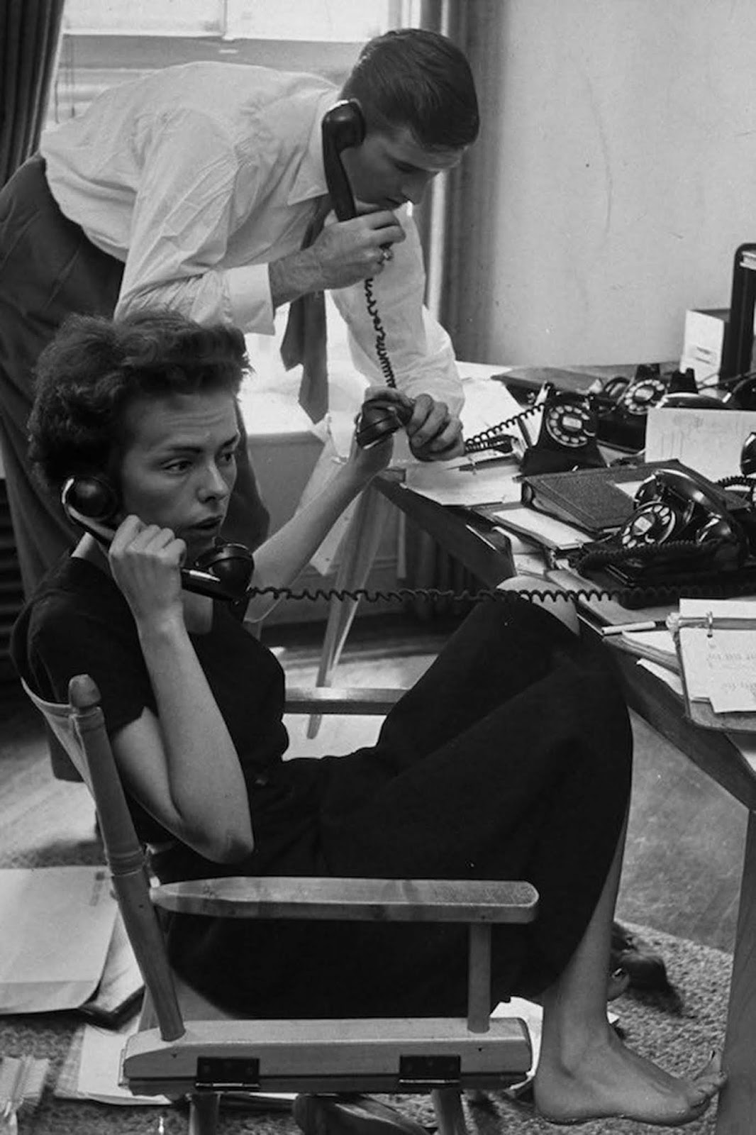 Ford Modeling Agency co-owner Eileen Ford and her husband answering calls requesting one of their 34 high fashion models. They're in her third floor office in New York. She is dressed in black, barefoot and has her hair cut short. 1948.