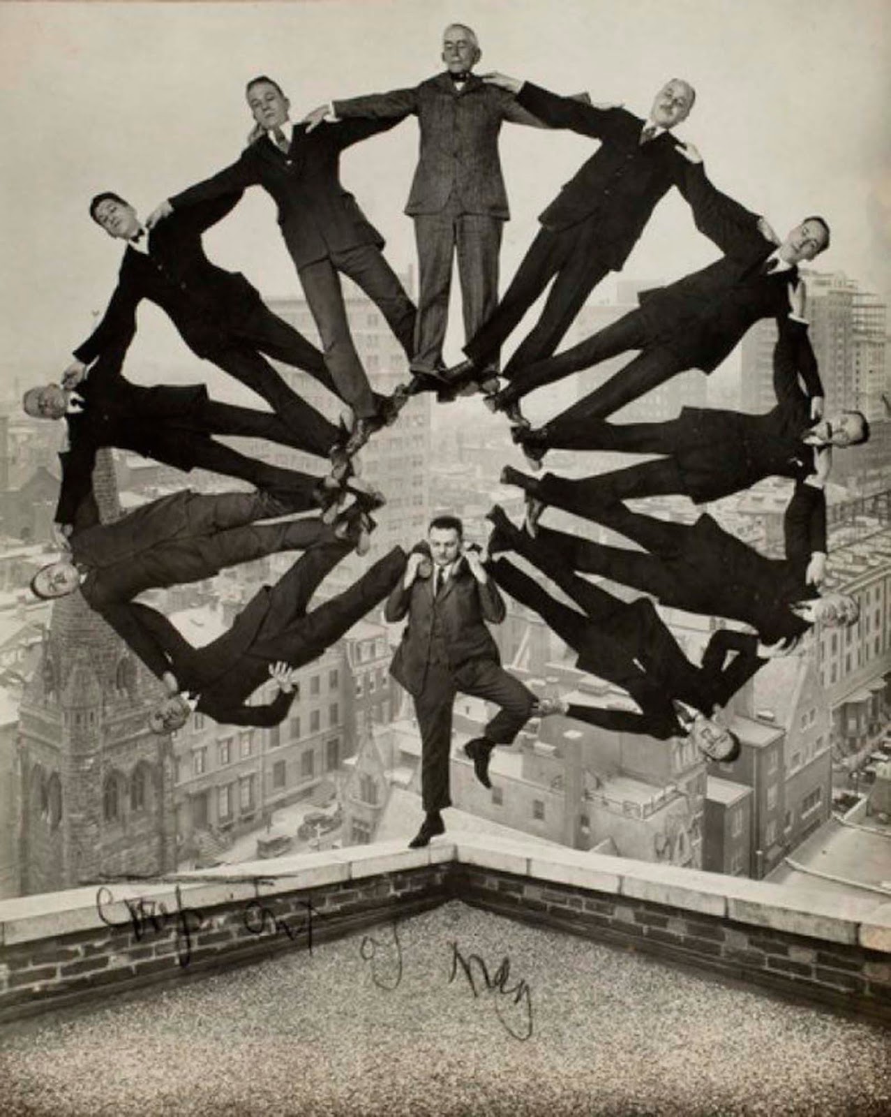 Man on rooftop with 11 men in formation on his shoulders. 1930.