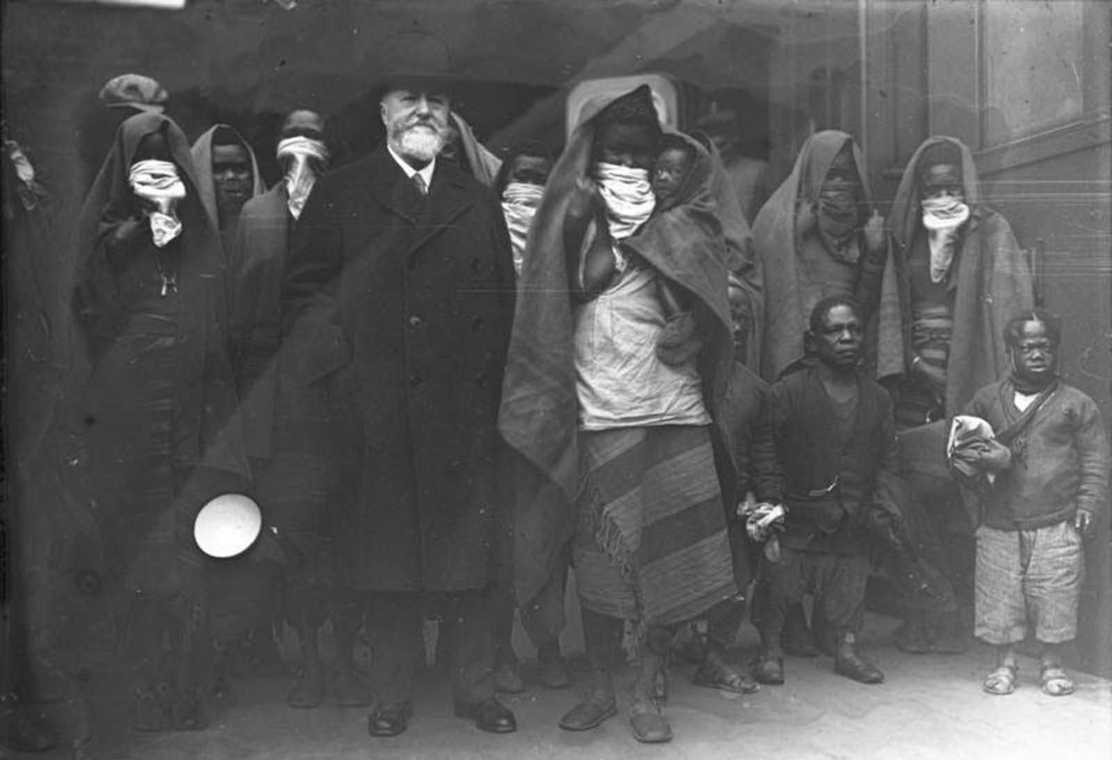 Professor Lutz Heck, director of the Berlin Zoo, arrives in Berlin, 1931. With him are members of the African Sara-Kaba tribe, who will soon be put on display. The scarves over the women's mouths are covering their lip plates.