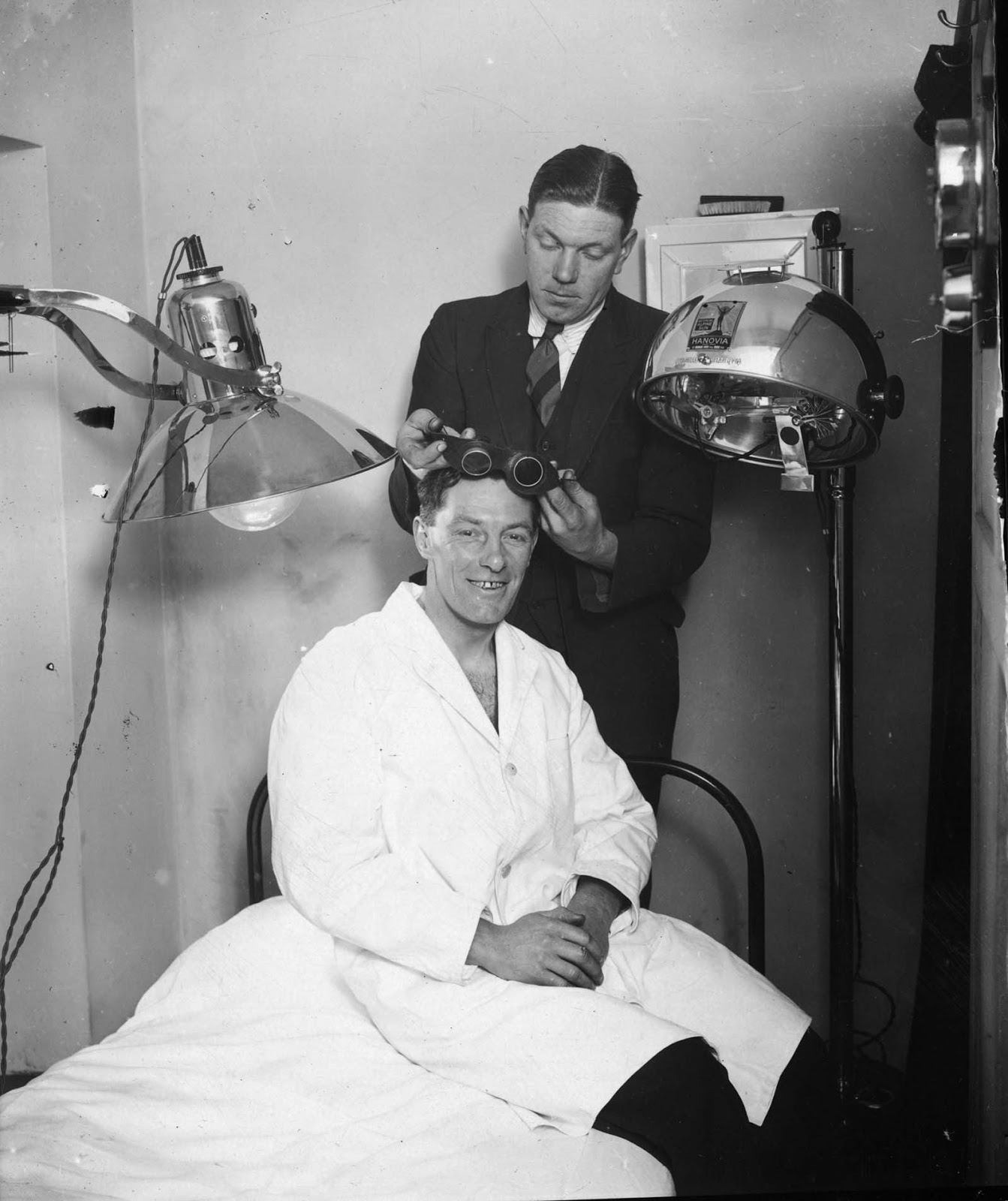 Northampton Town Football Club trainer fits the team captain, W Watson, with some goggles for a course of ultra-violet ray treatment in preparation for an FA Cup tie with Millwall. 1929.