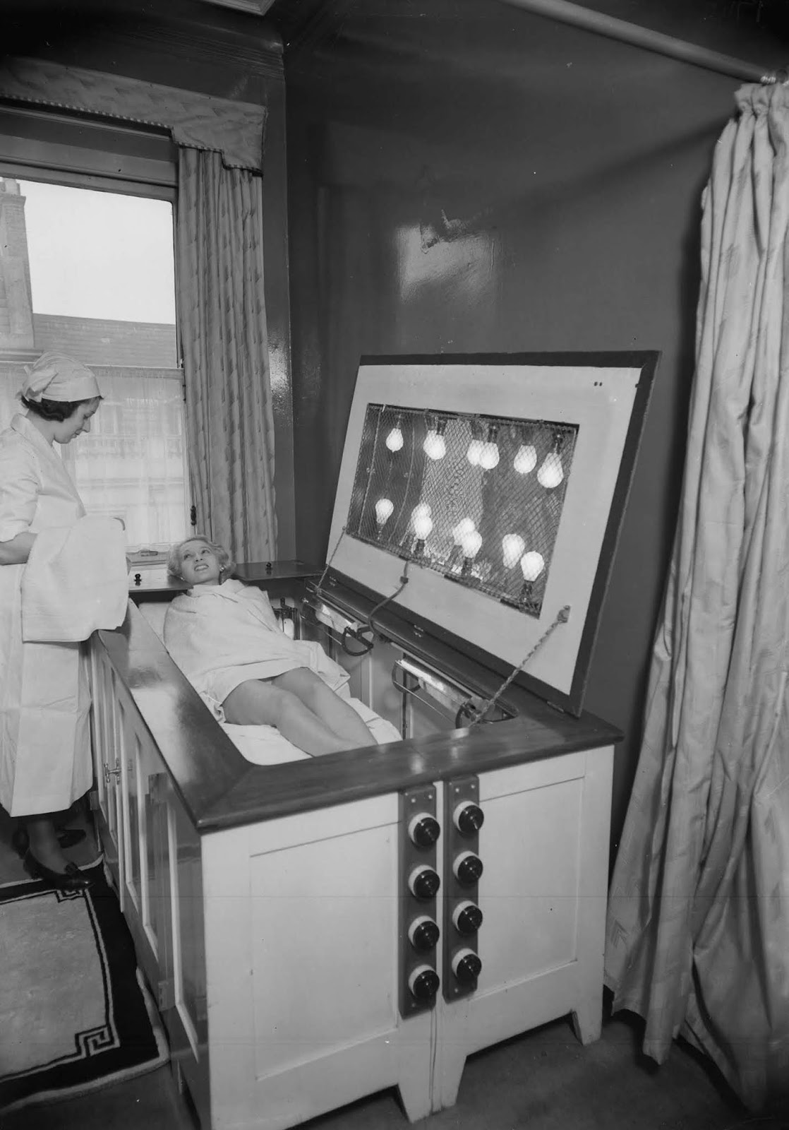 A nurse handing a towel to a woman on a sunbed. 1934.