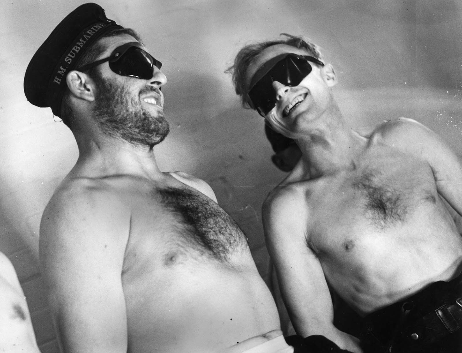 Two crew members of a British submarine spend a session under a sunlamp whilst ashore, to make up for the time they spend below the surface without being subjected to sunlight. 1940.