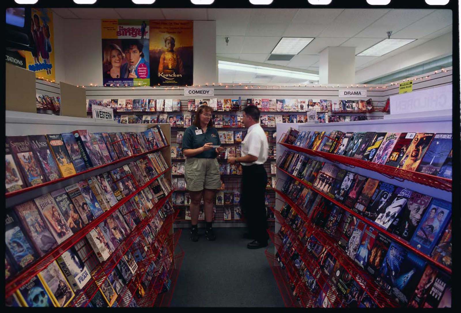 Store manager Ken Broderius talks with an employee in the video rental department of the Rosaurs Super One.