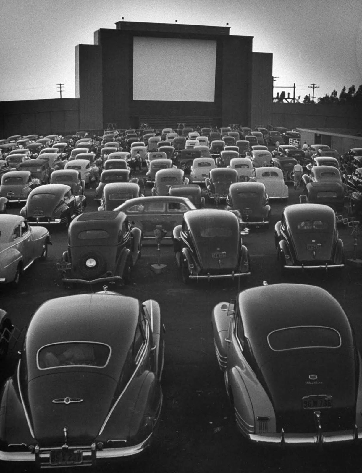 Cars filling lot at new Rancho Drive-In Theater at dusk before the start of the feature movie.