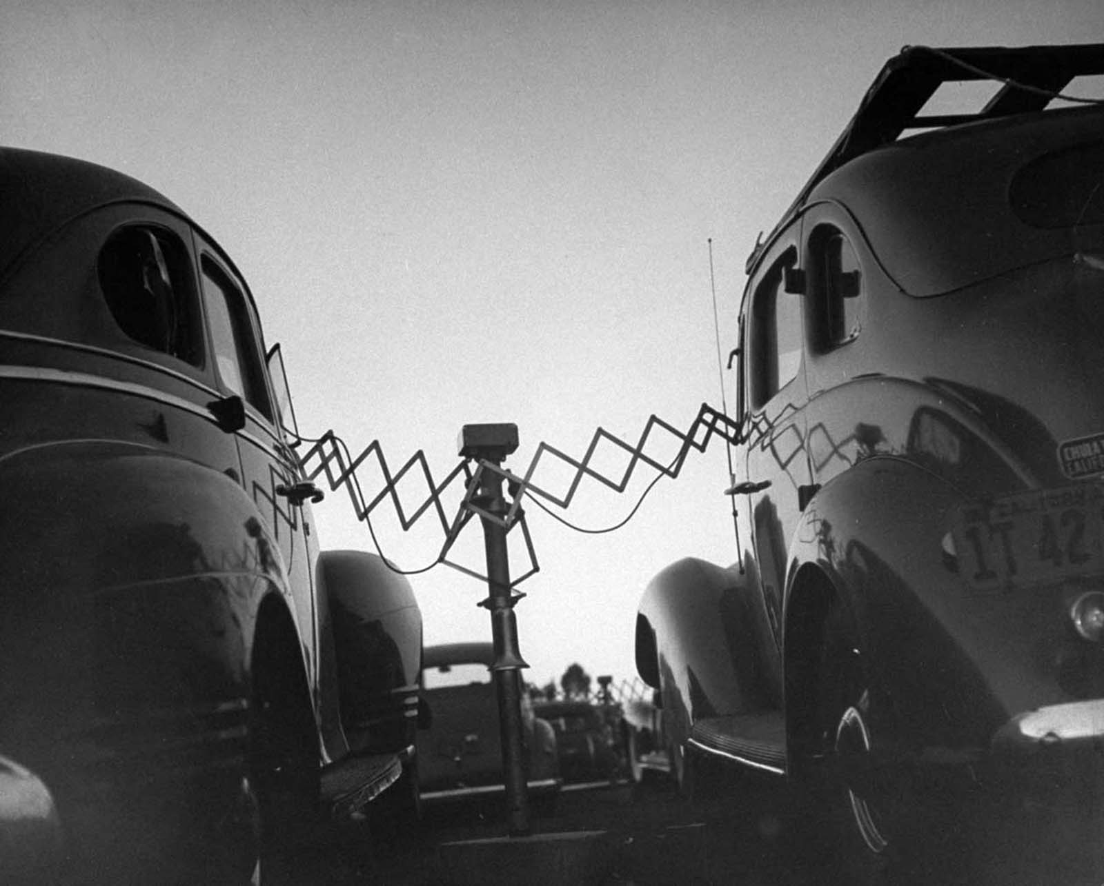 Cars parked at Rancho Drive-In Theater with the accordion-like fulcrum arms of movie speakers reaching into each driver’s front window, which they will push back onto the central post when the movie is over.