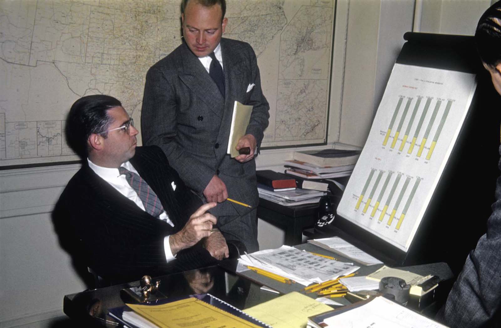 A plethora of yellow pencils litters this man's desk as he investigates detailed statistics relating to a client campaign.