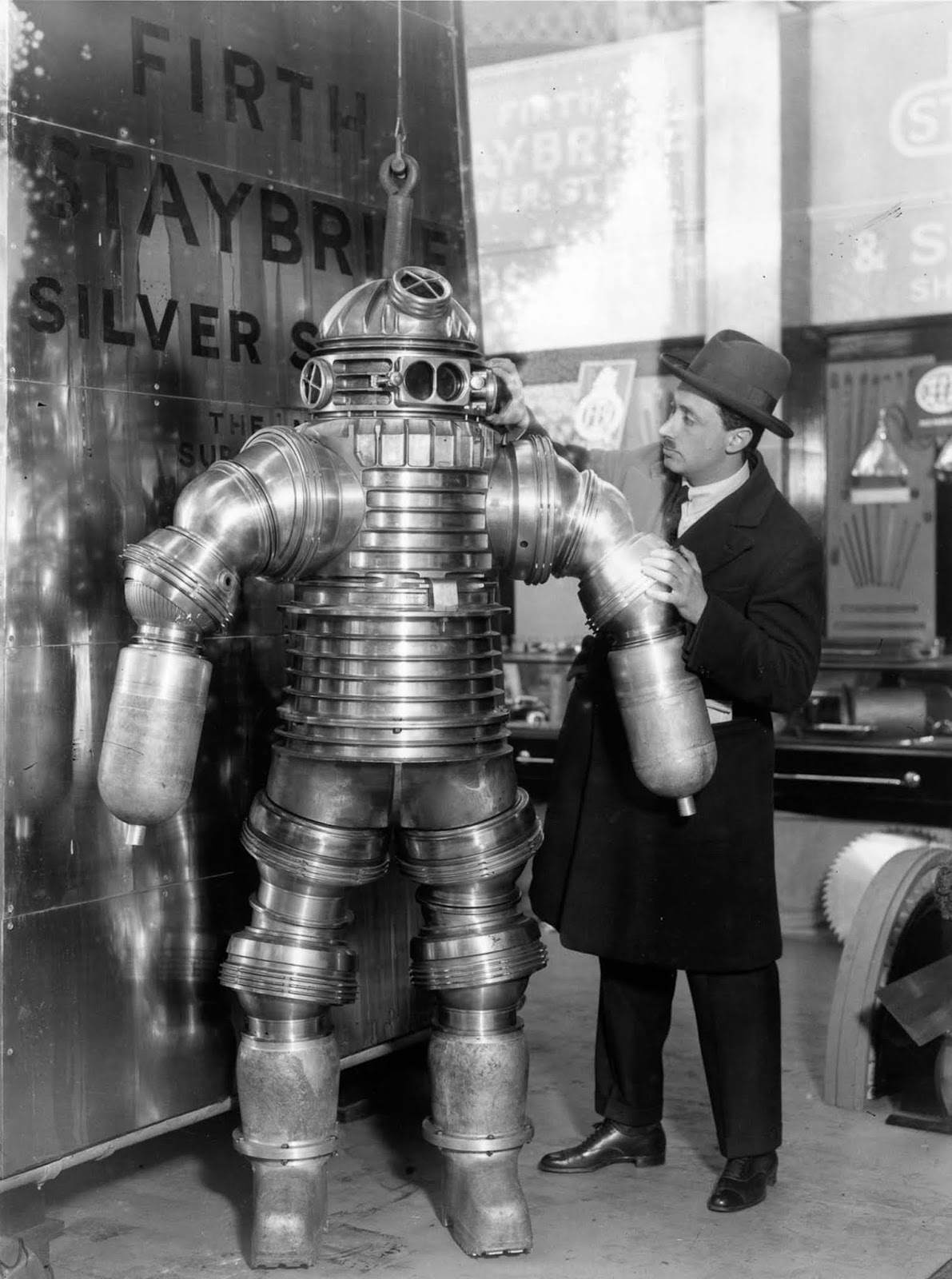 Inventor J. S. Peress explains the workings of his new rustless diving suit, made of Staybrite Silver Steel, at the Olympia Shipping Exhibition in London. The suit weighs 550 pounds and can work at a depth of 650 feet. 