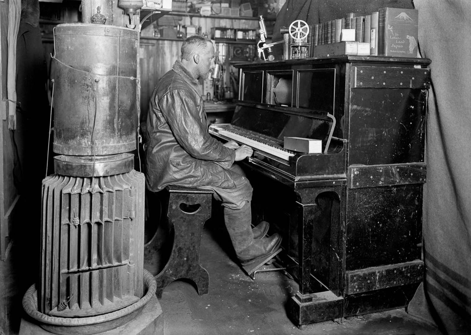 Dog handler Cecil Meares at the piano in the hut. January, 1912.
