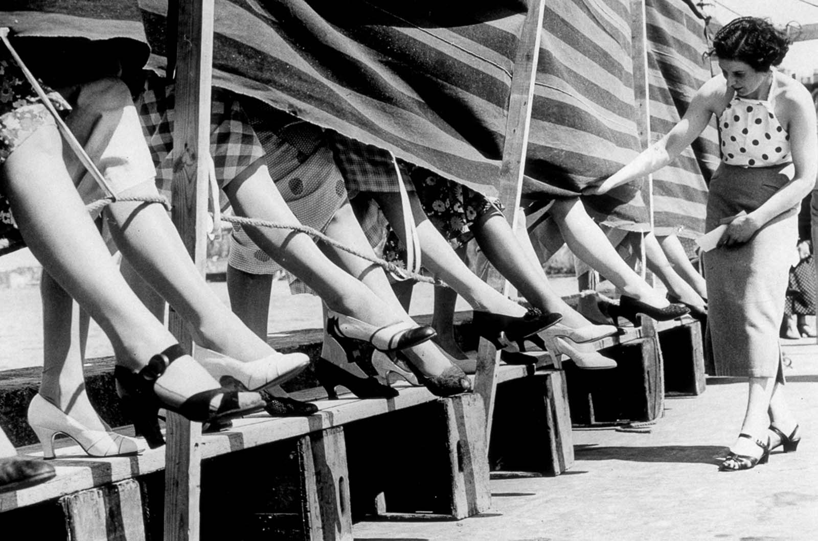 A woman judges the best ankle competition at the Cliftonville open air swimming pool, Margate, in 1936.