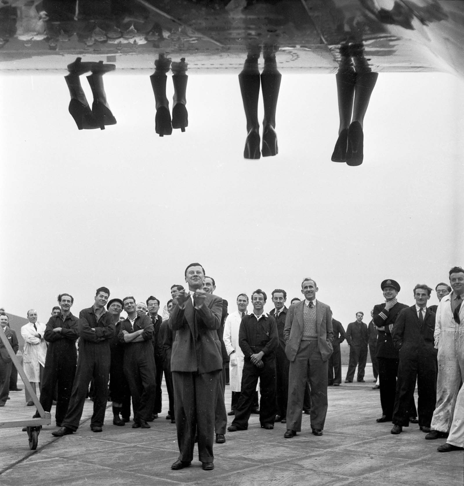 The legs of contestants in a 'Miss World' beauty competition dangle over the wing of a BOAC Comet airplane. 1953.