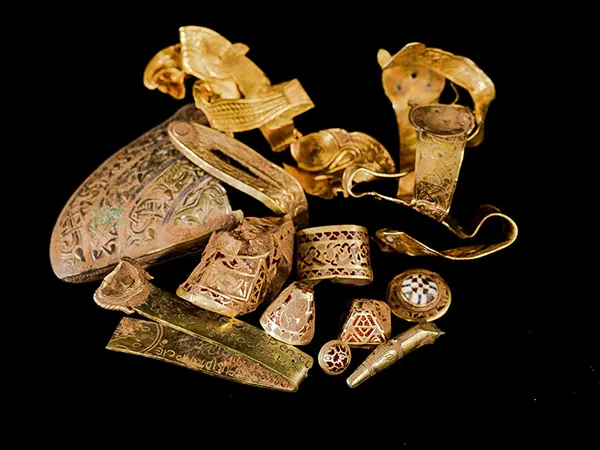 A selection of highlight pieces from the Staffordshire Hoard (top) and a gold sword hilt fitting with cloisonné garnet inlay, uncleaned by conservators, still showing traces of soil.