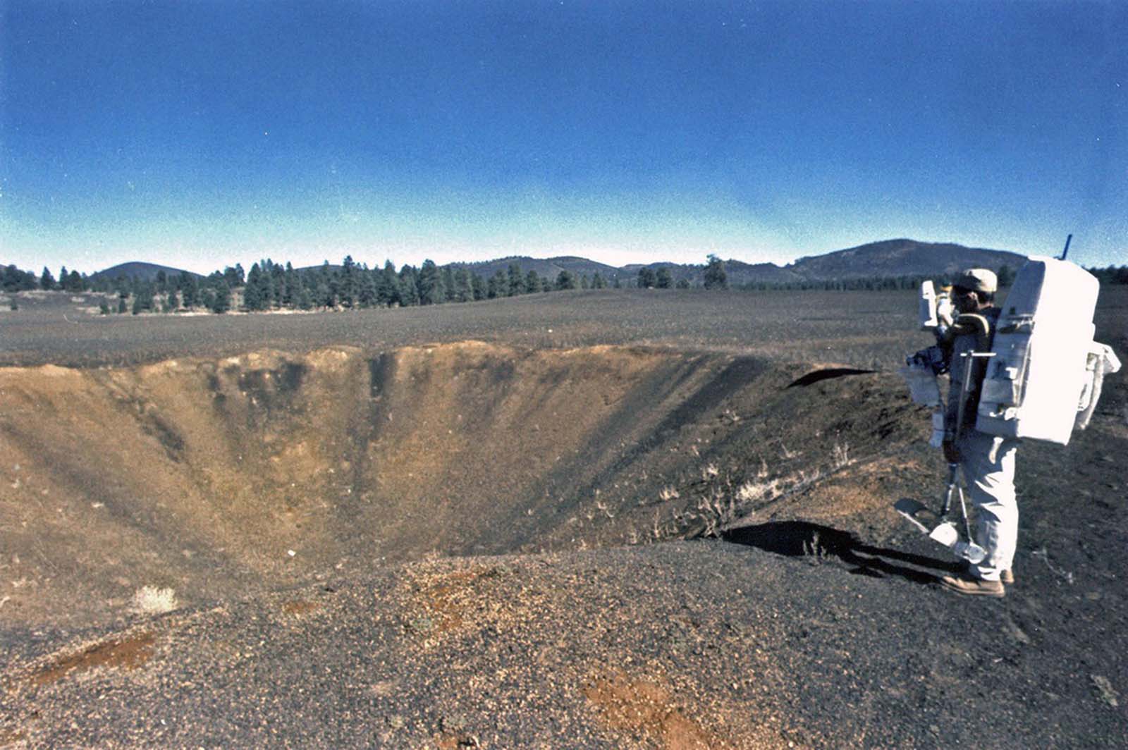 The astronauts Harrison Schmitt and Gene Cernan view a crater within the Cinder Lake Crater Field. Both men went on to walk on the surface of the moon in 1972, during Apollo 17.