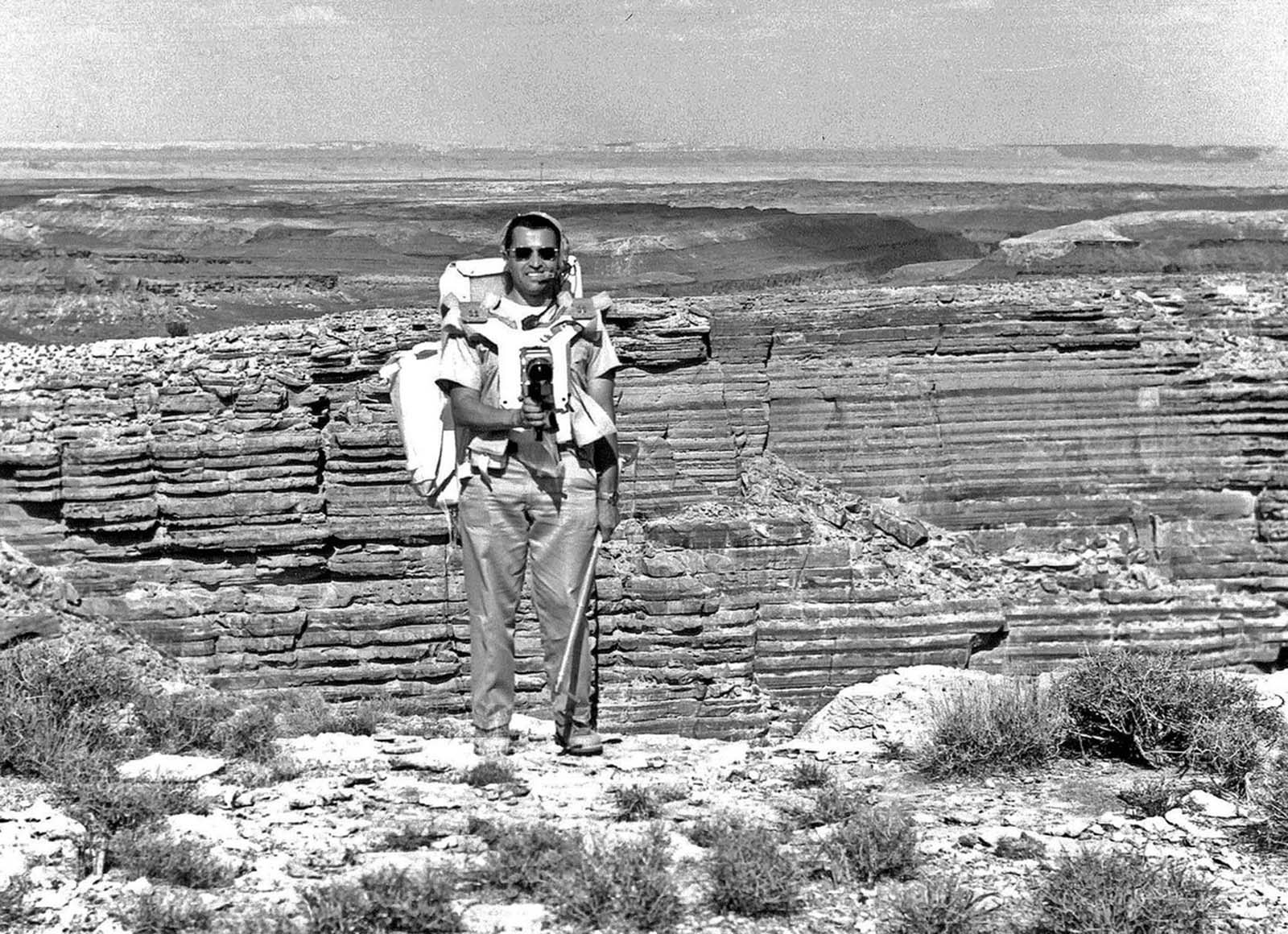 The Apollo 17 astronaut Harrison Schmitt stands on the edge of an erosional canyon that was used to simulate the large Hadley Rille at the Apollo 15 landing site. Schmitt was originally part of the Apollo 15 backup crew, and later slated to fly in Apollo 18. When that mission was canceled, Schmitt was moved up to Apollo 17 due to his previous work and studies as a professional geologist.