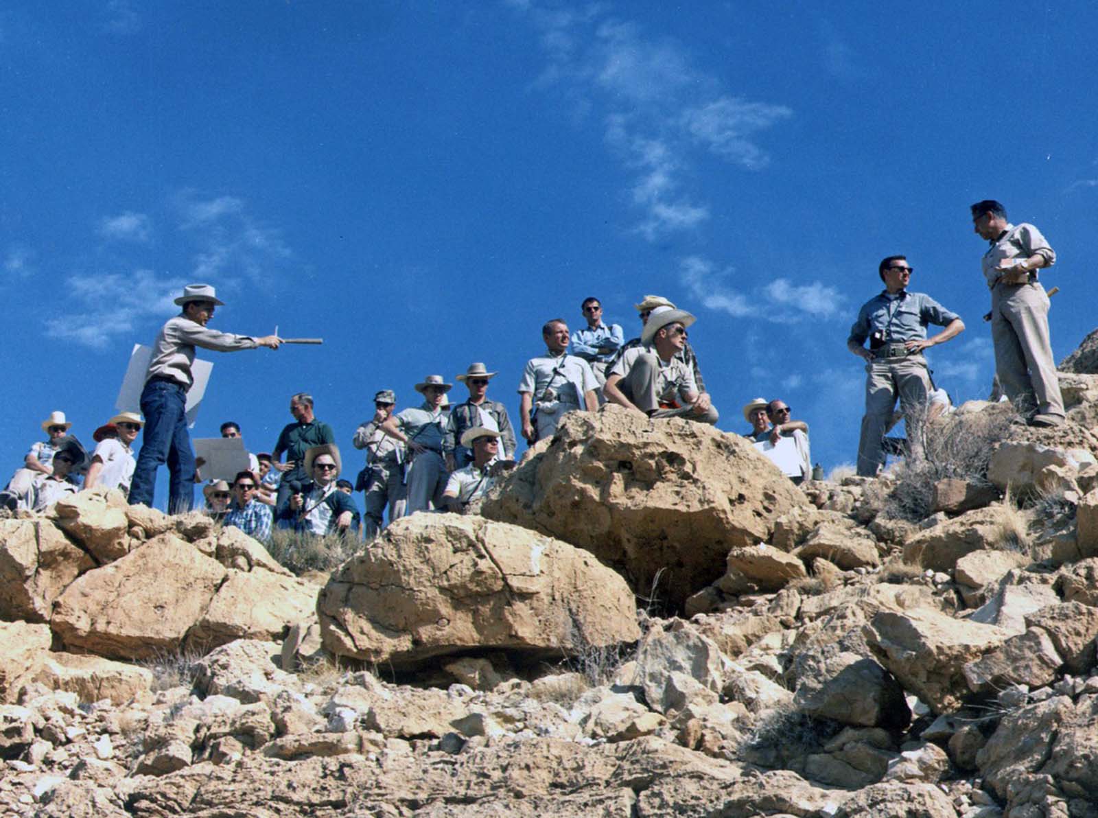 The astrogeologist Gene Shoemaker describes the geology of the rim ejecta of Arizona's Meteor Crater to a large group of astronauts during a field trip in May 1967.